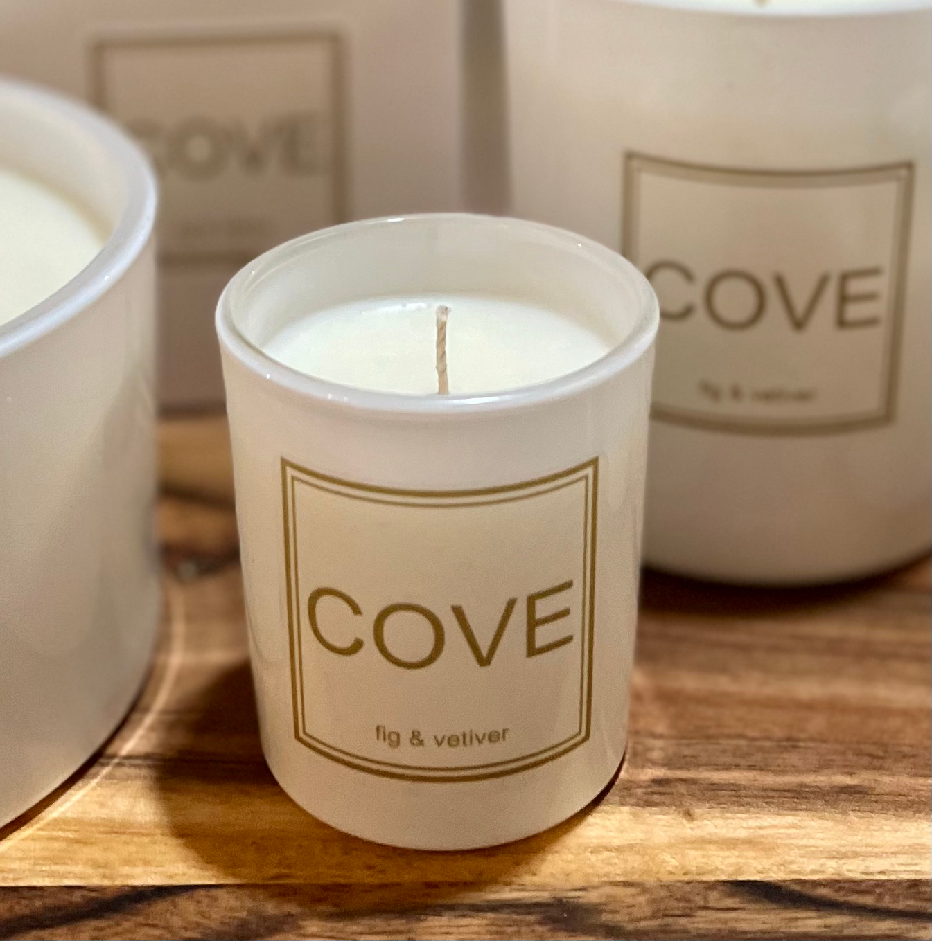 Candle labeled 'Cove' with 'fig & vetiver' scent on a wooden surface