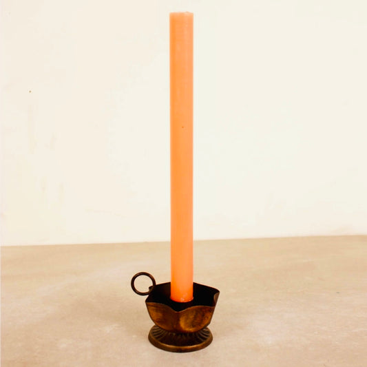 Tall peach-colored candle in a decorative Frill Candle Holder on a beige surface with a light beige background