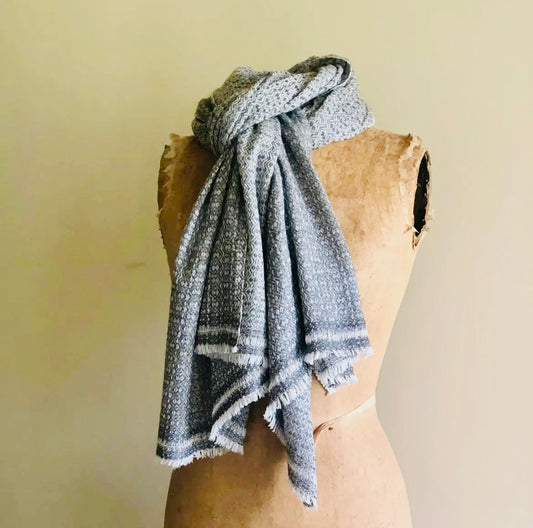 Grey patterned scarf draped over a wooden mannequin against a beige background