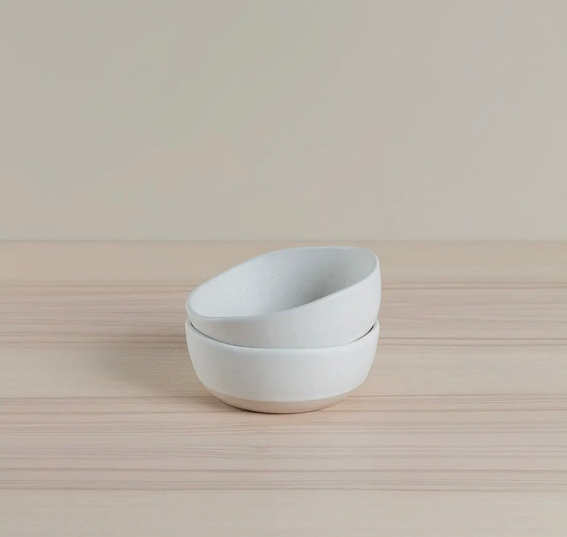 Two white Organics Cereal Bowls stacked on a beige surface with a neutral background