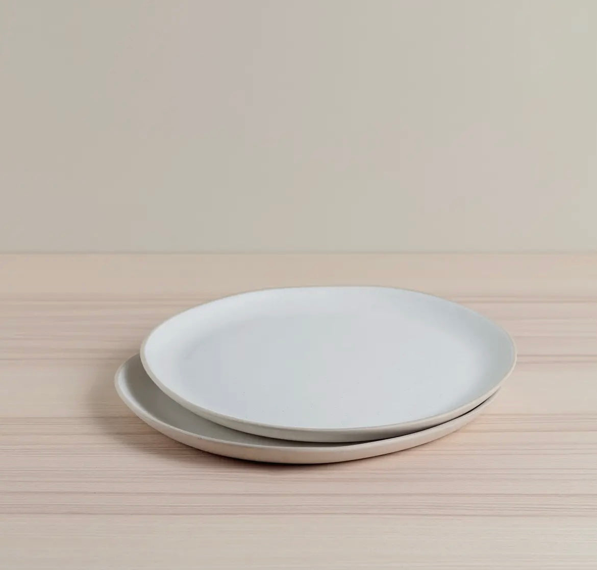 Two Organics Dinner Plates stacked on a wooden surface with a neutral background