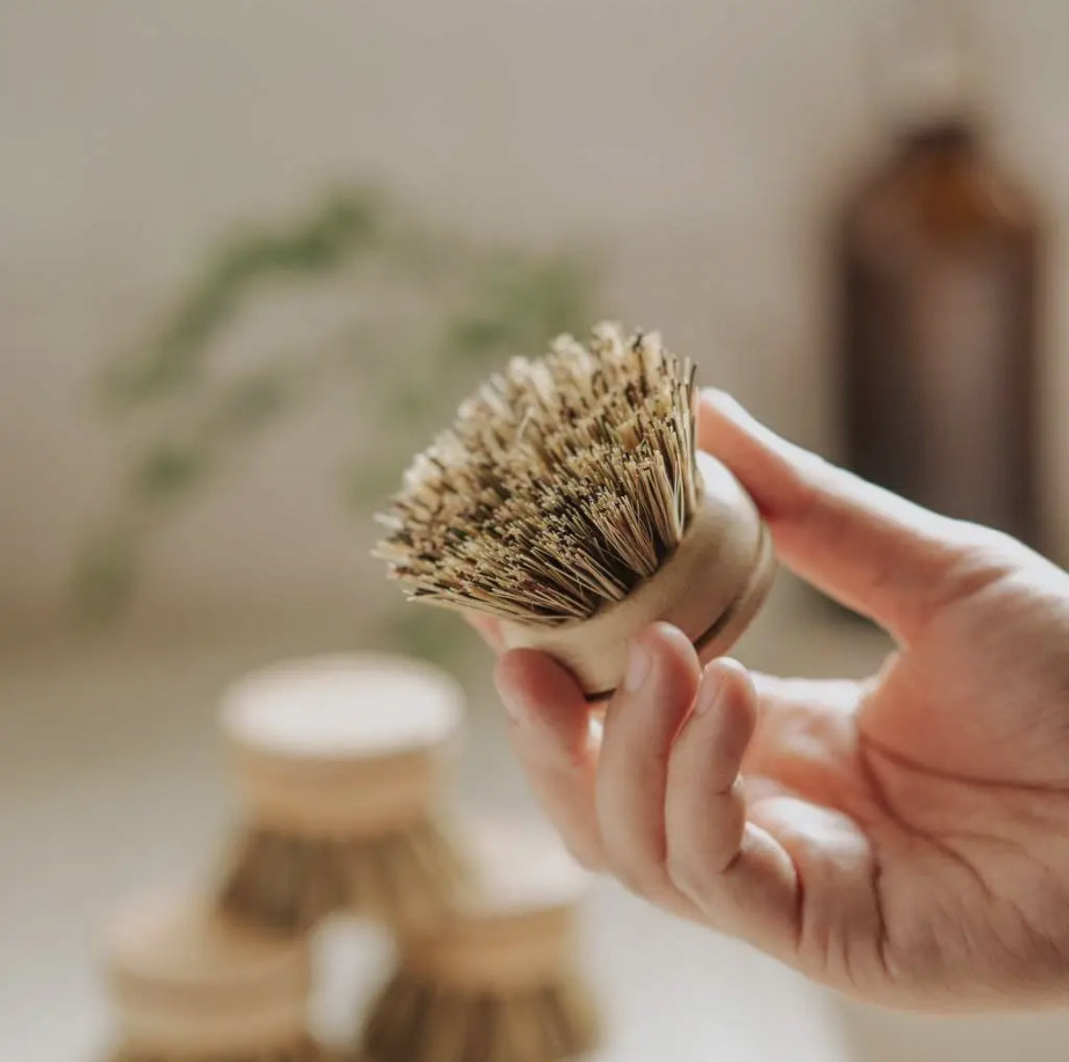Hand holding a wooden brush with bristles against a blurred indoor background