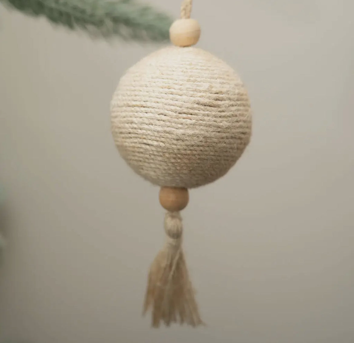 Decorative ball with wooden beads and tassel on a neutral background