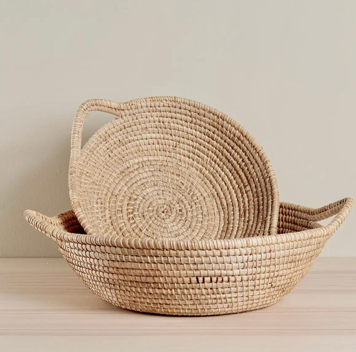 Woven basket with a lid on a light wooden surface against a neutral background
