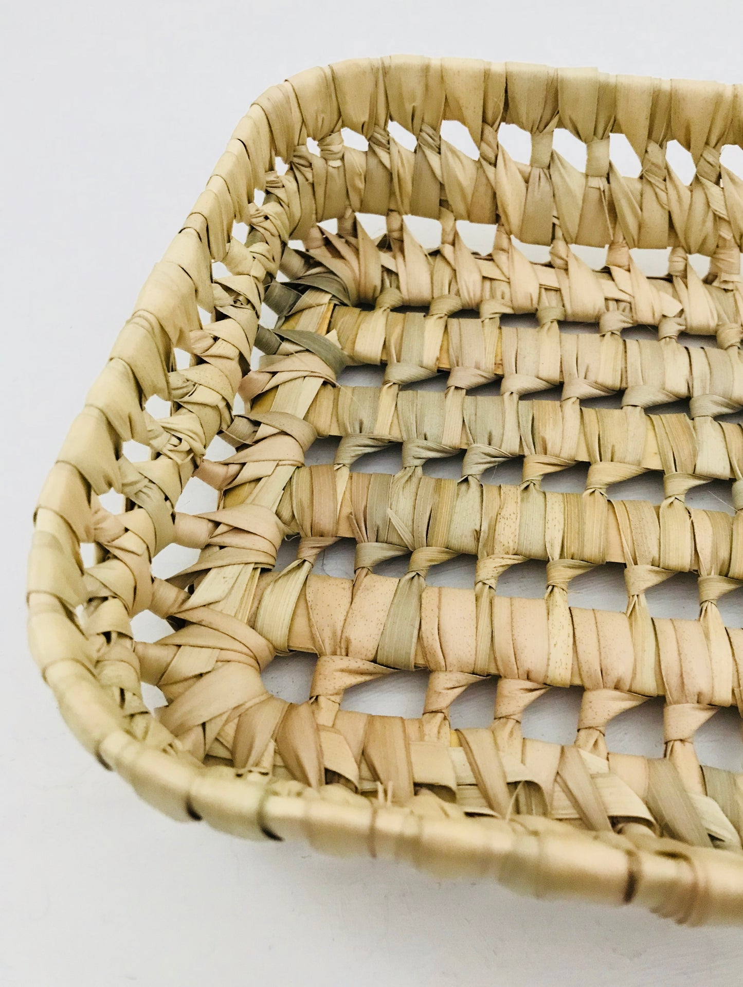 Woven basket with a natural beige color on a light gray background