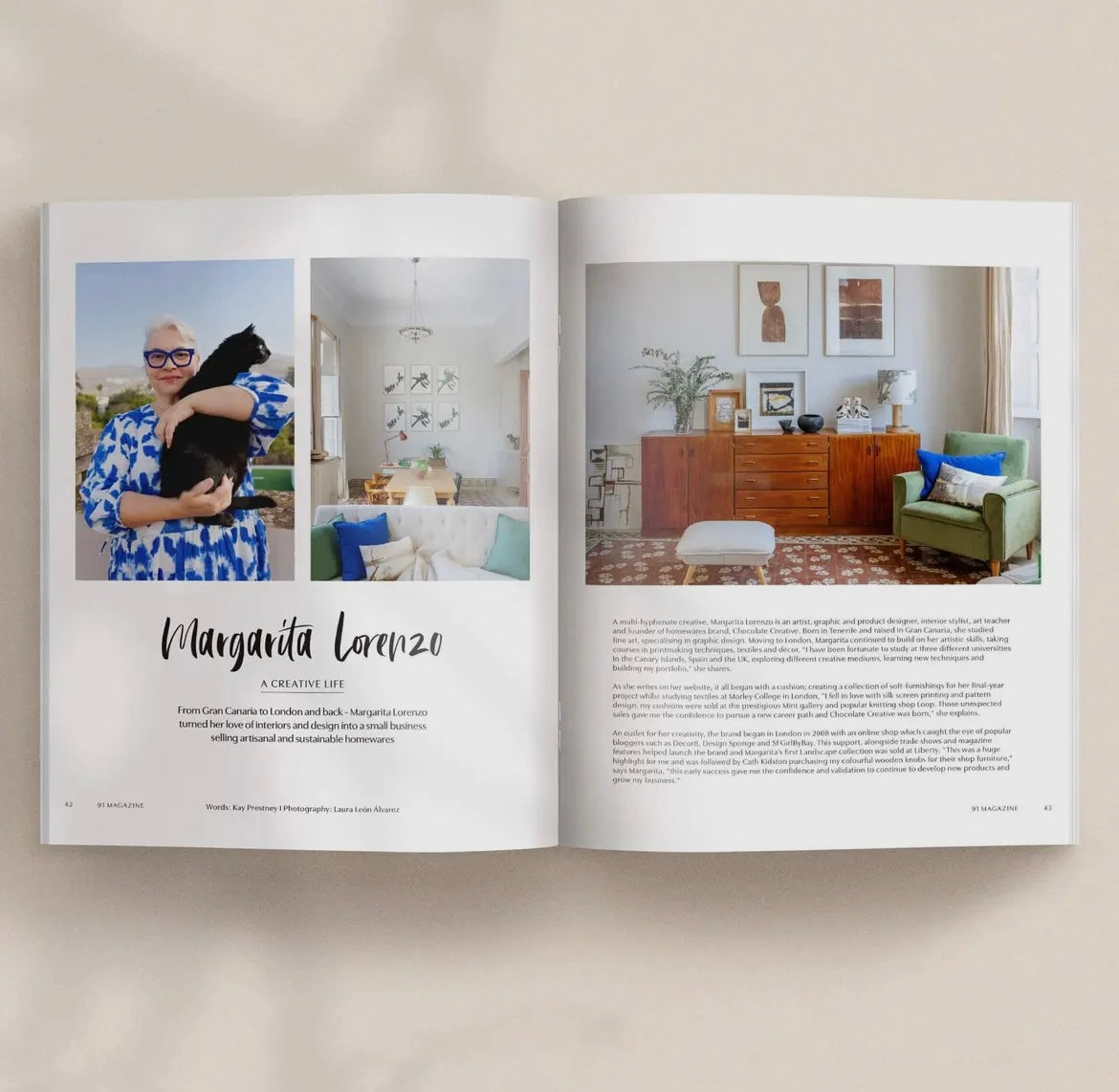 Open magazine with interior design layout featuring a woman, black cat, and living room.