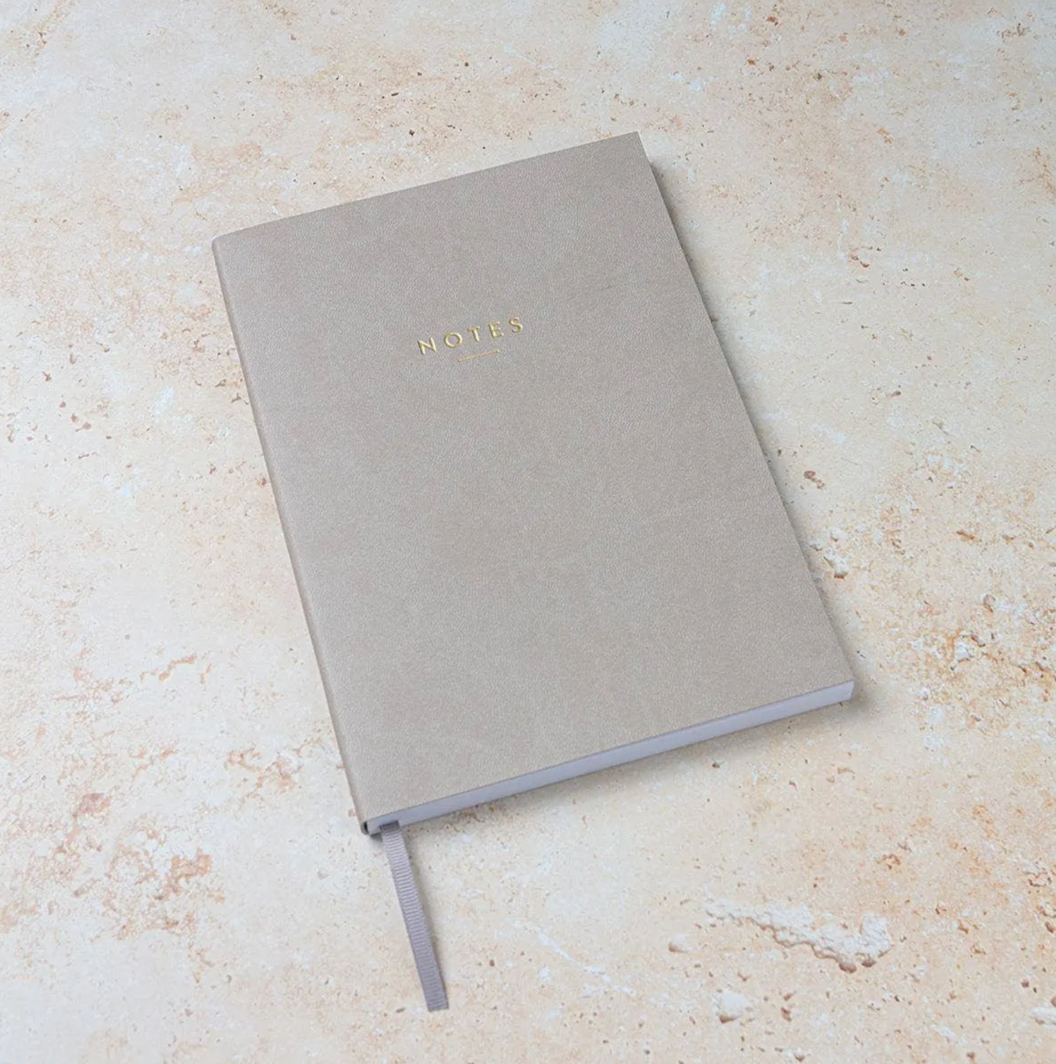 Grey notebook with 'NOTES' on a beige surface
