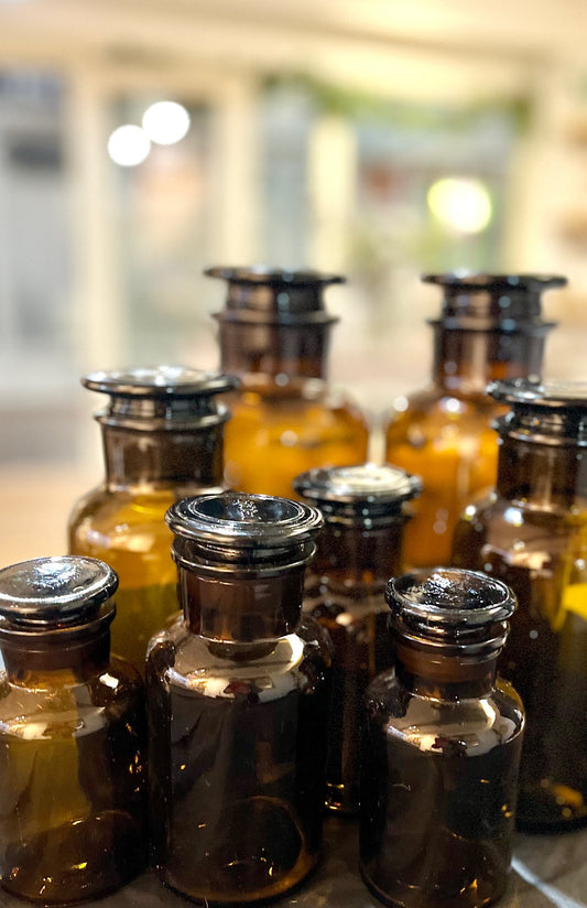 Collection of glass Apothecary Bottle Storage Jars with metal caps on a blurred background