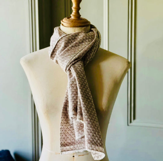 Brown patterned scarf on a mannequin against a neutral wall.
