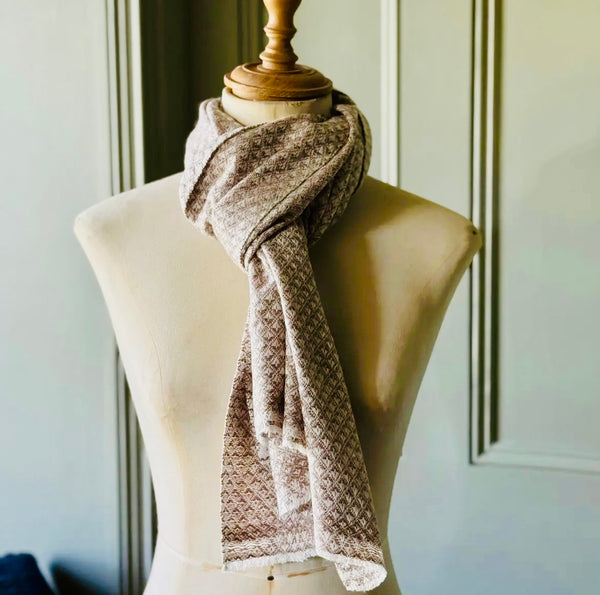 Brown patterned scarf on a mannequin against a neutral wall.