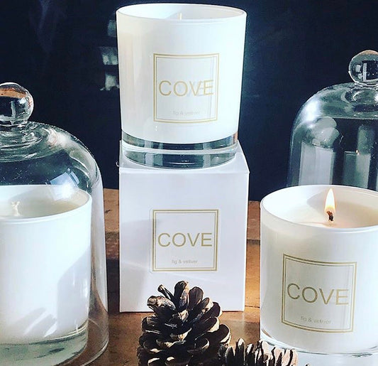 Cove candles with packaging and decorative elements on a wooden surface