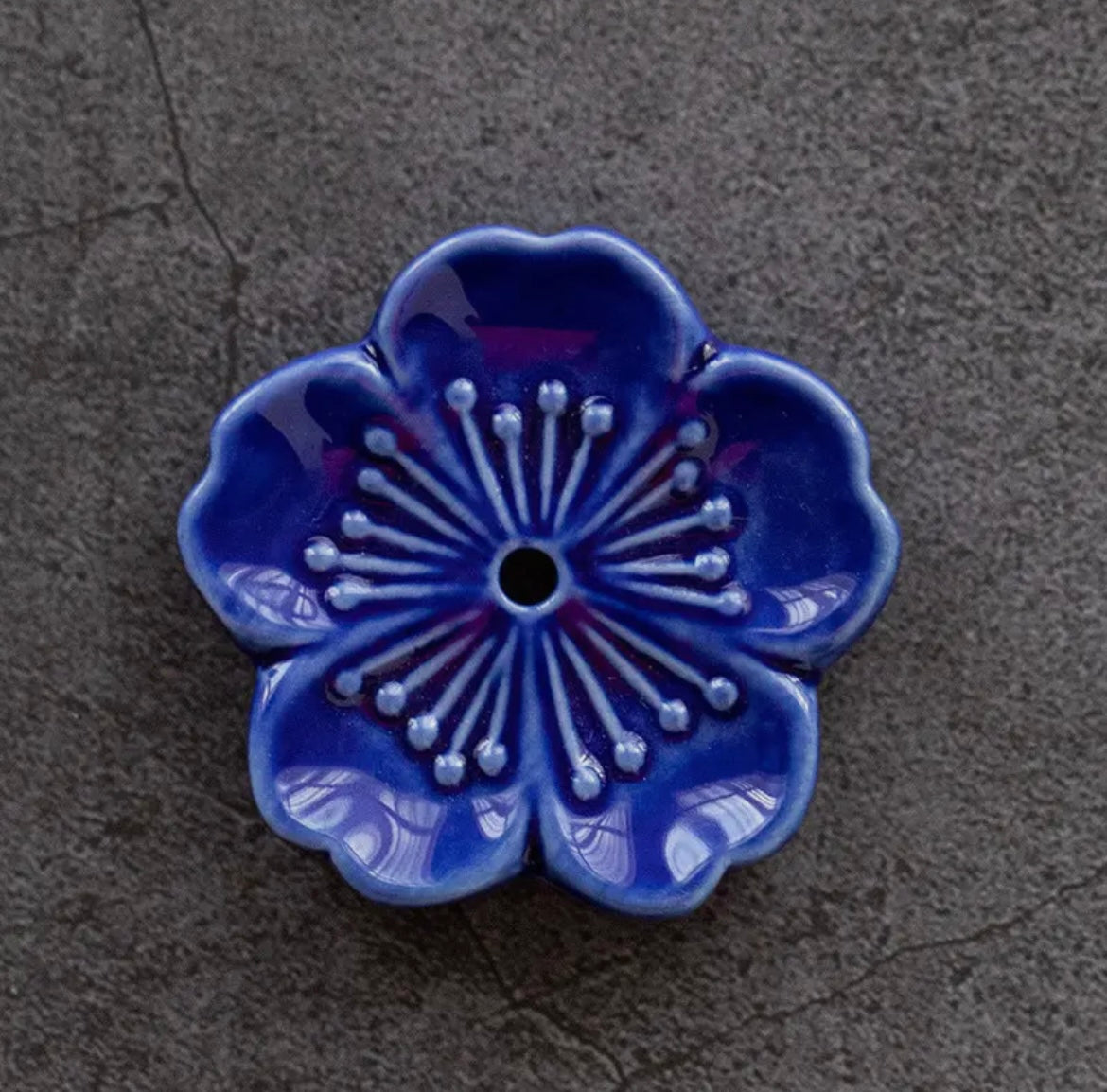 Blue ceramic flower-shaped object on a textured gray surface