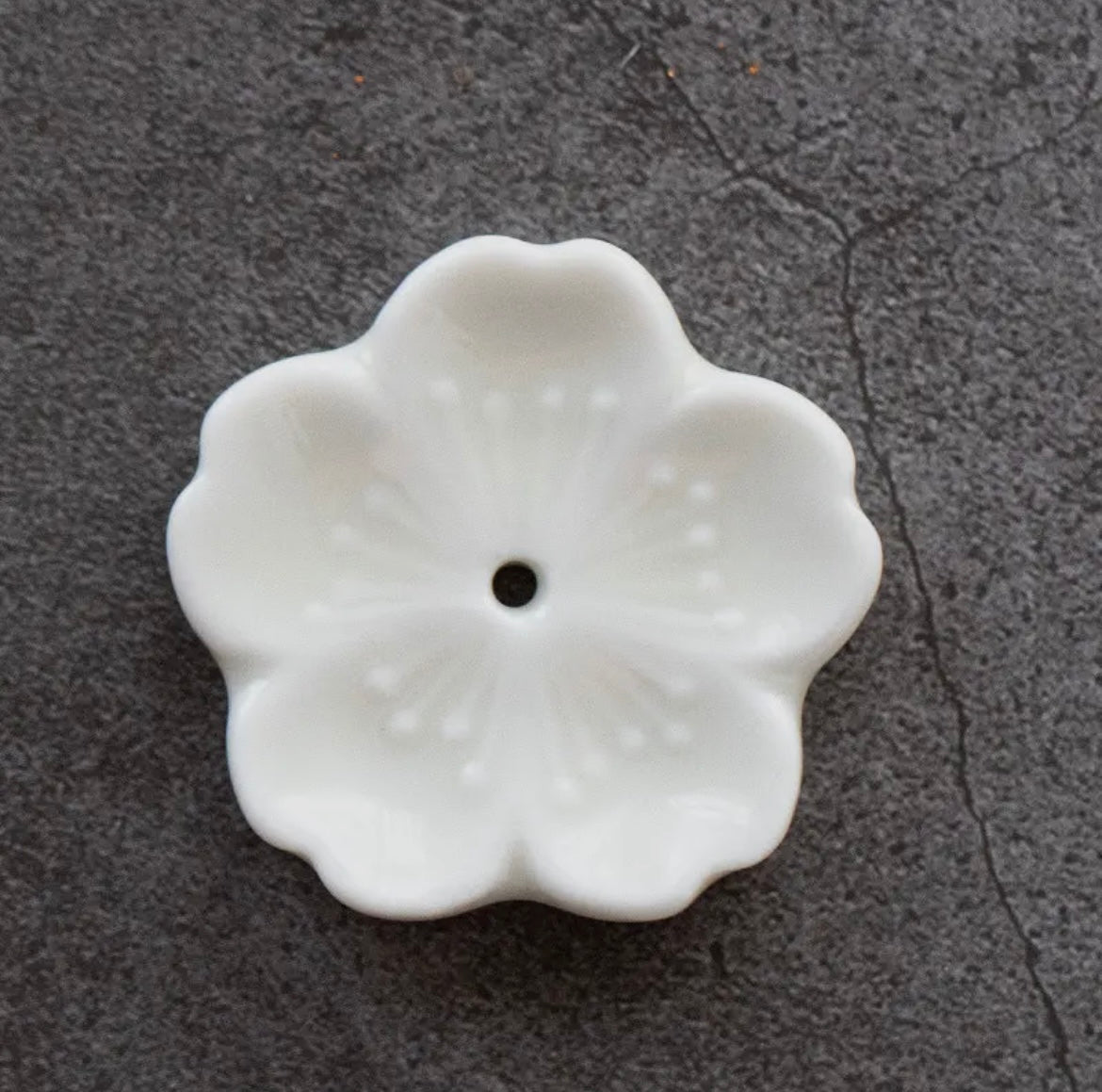 White ceramic flower-shaped object on a dark textured surface