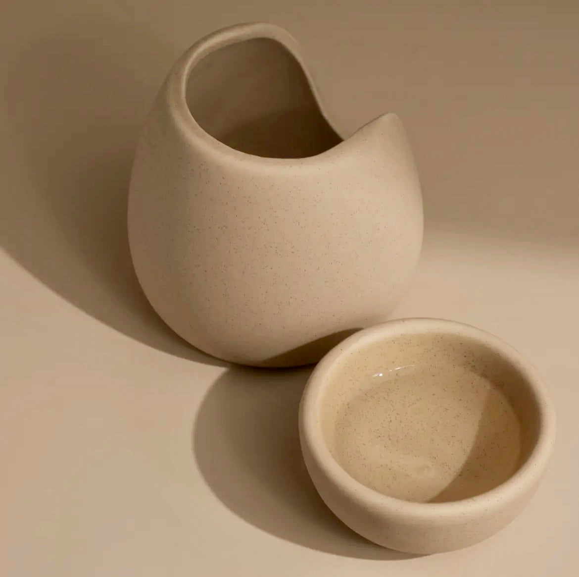 Two beige ceramic pots on a neutral background
