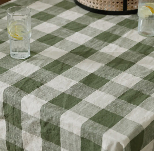 Green and white checkered throw with a glass of water on a table.