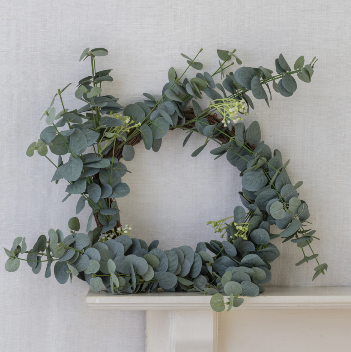Green eucalyptus wreath on a white surface with a light gray background