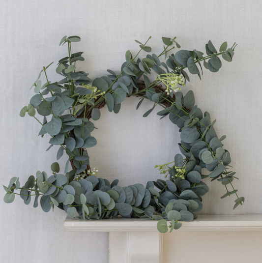 Green eucalyptus wreath on a white surface with a light gray background