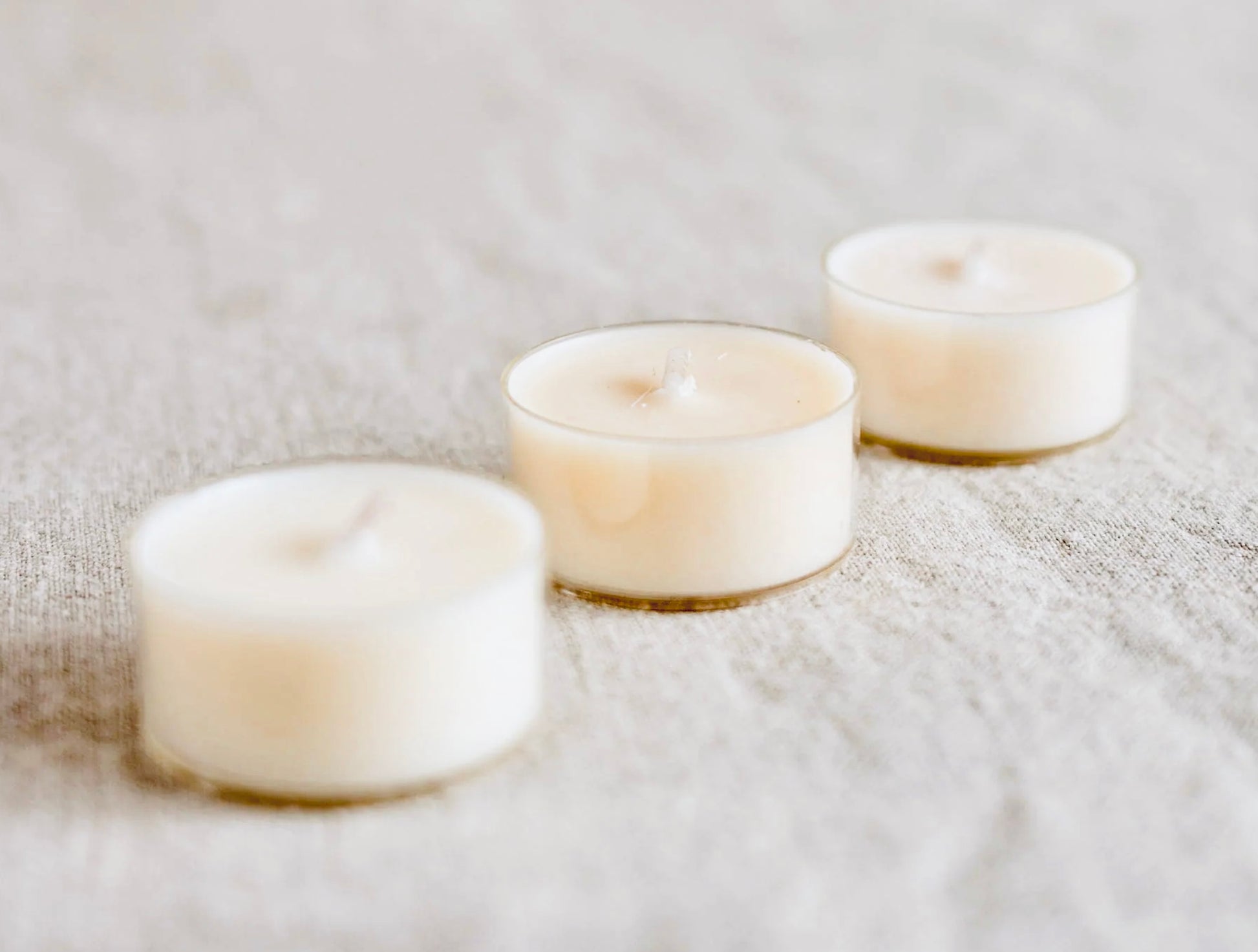 Three small white candles on a textured surface
