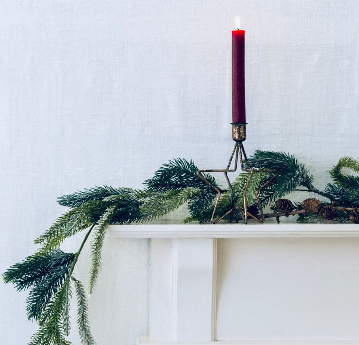 Decorative candle with greenery on a white surface