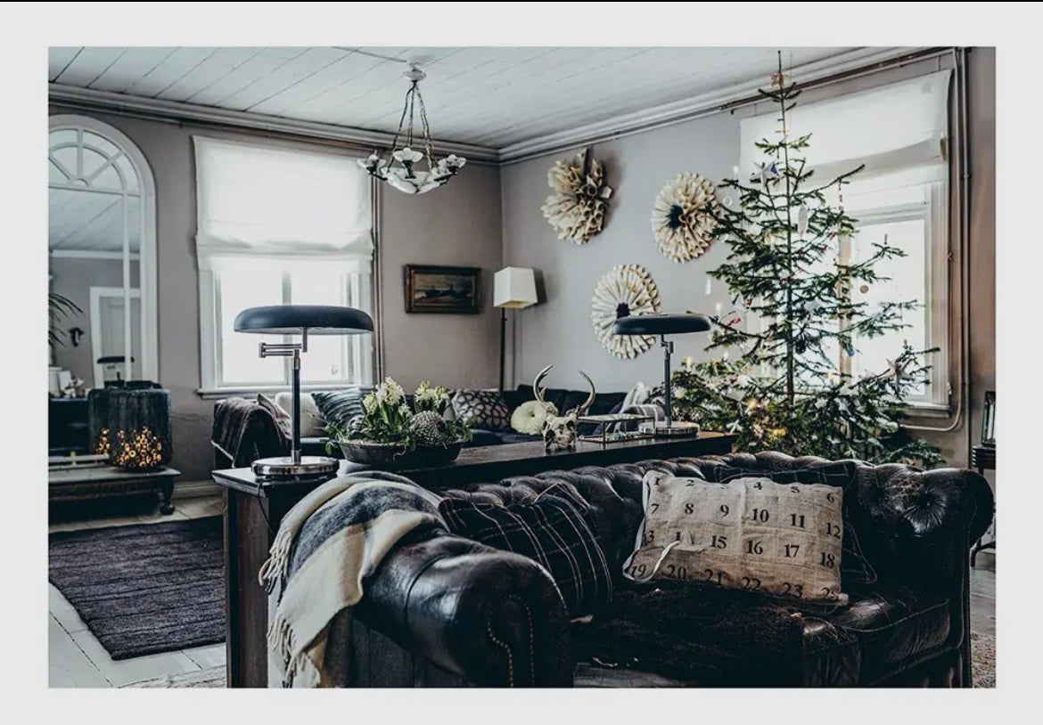 Cozy living room with a Christmas tree, decorated walls, and a dark leather sofa.