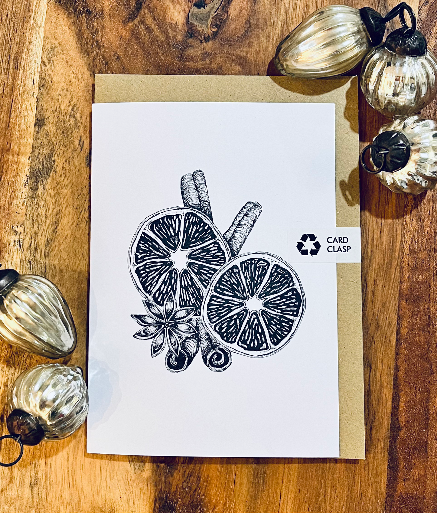 Card with black and white illustration of lemon slices and cinnamon sticks on a wooden surface with decorative pumpkins.