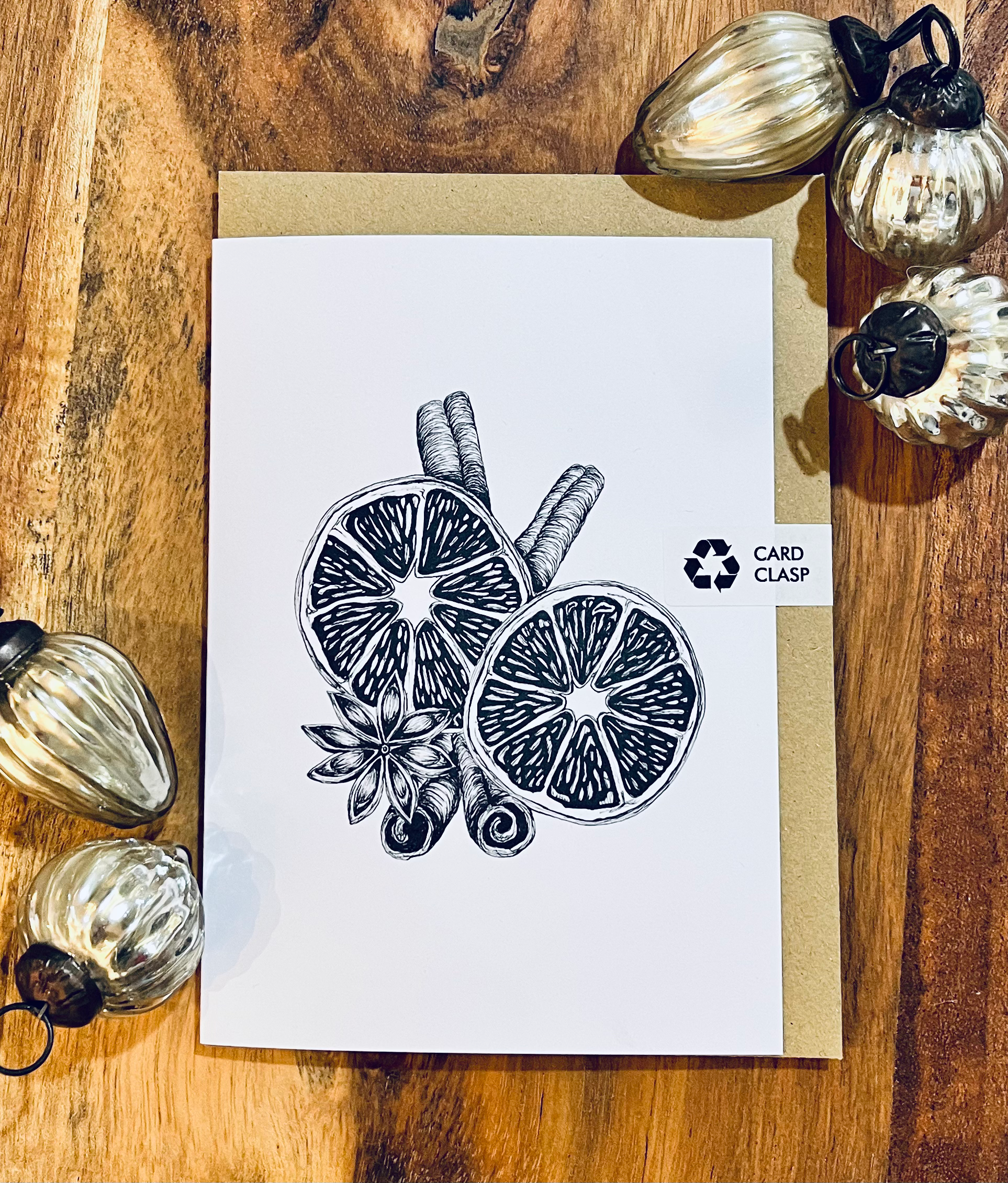 Card with black and white illustration of lemon slices and cinnamon sticks on a wooden surface with decorative pumpkins.