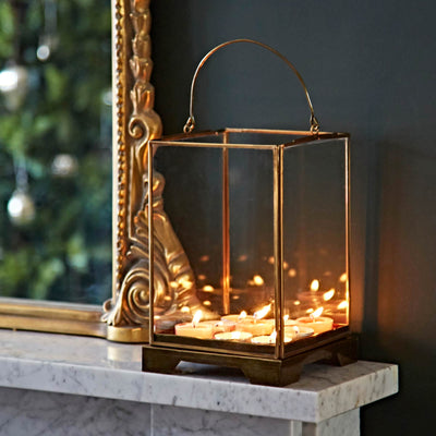 Decorative lantern with candles on a marble surface next to a mirror