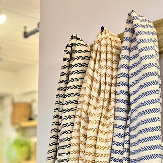 Three striped scarves hanging on a rack with a blurred indoor background