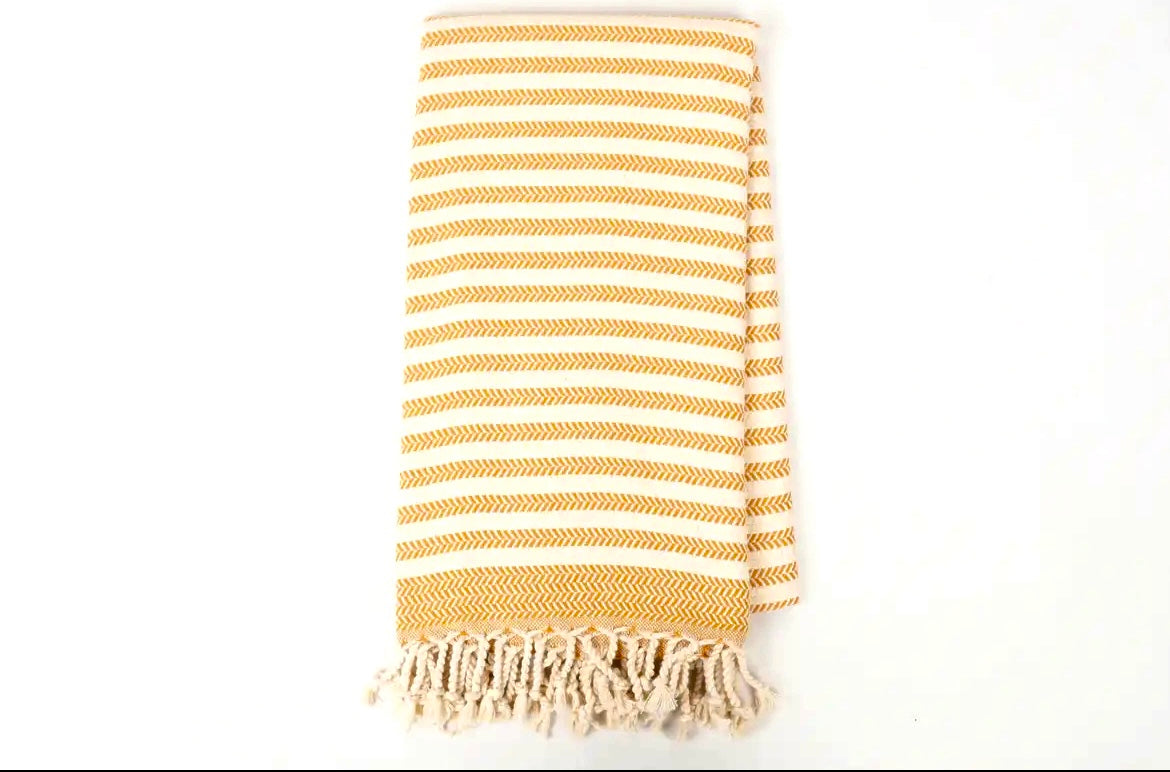 Yellow and white striped towel with fringes on a white background