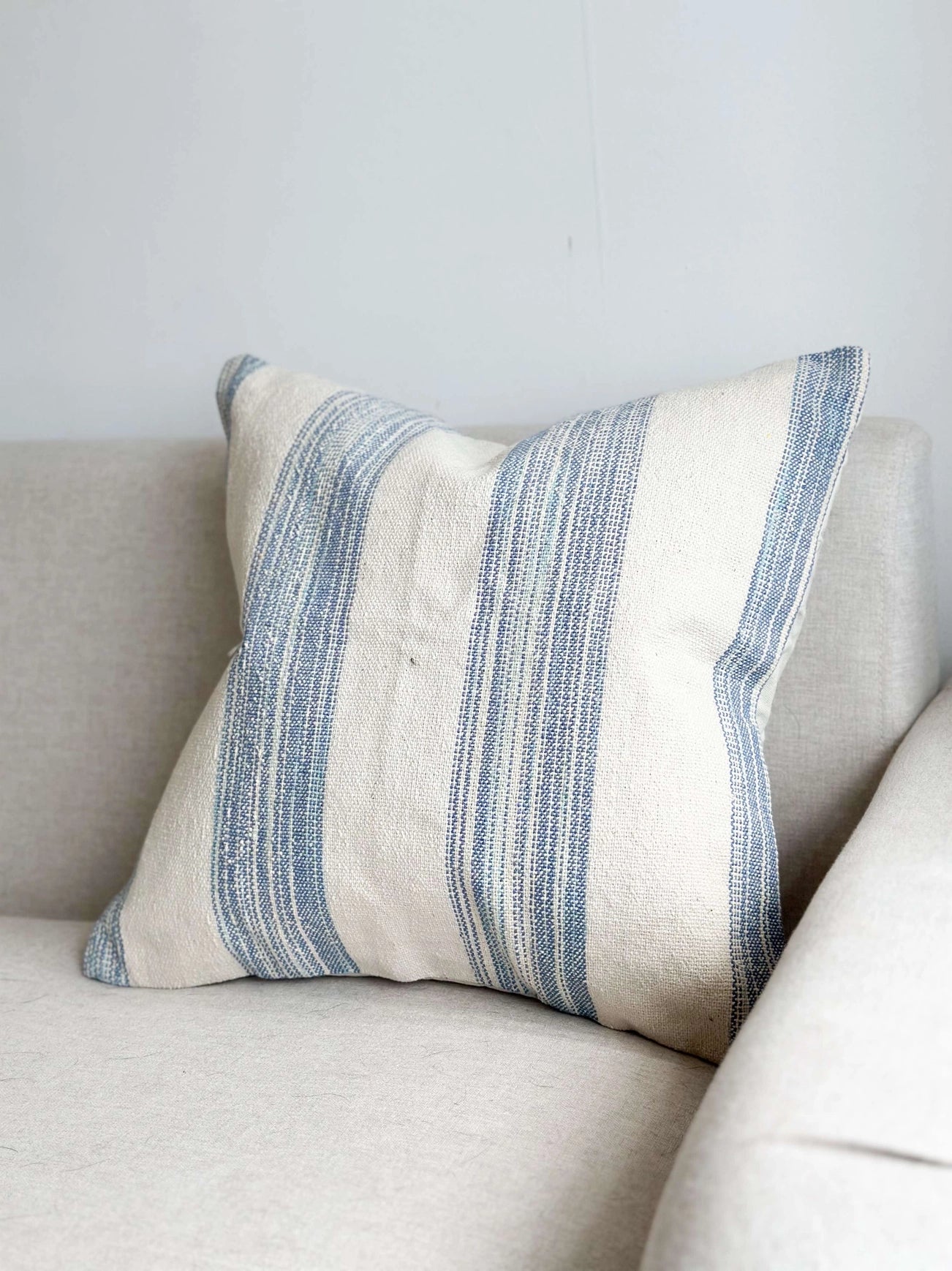 Striped pillow on a beige sofa against a light gray wall