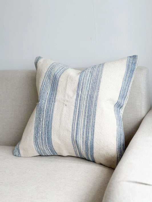 Striped pillow on a beige sofa against a light gray wall
