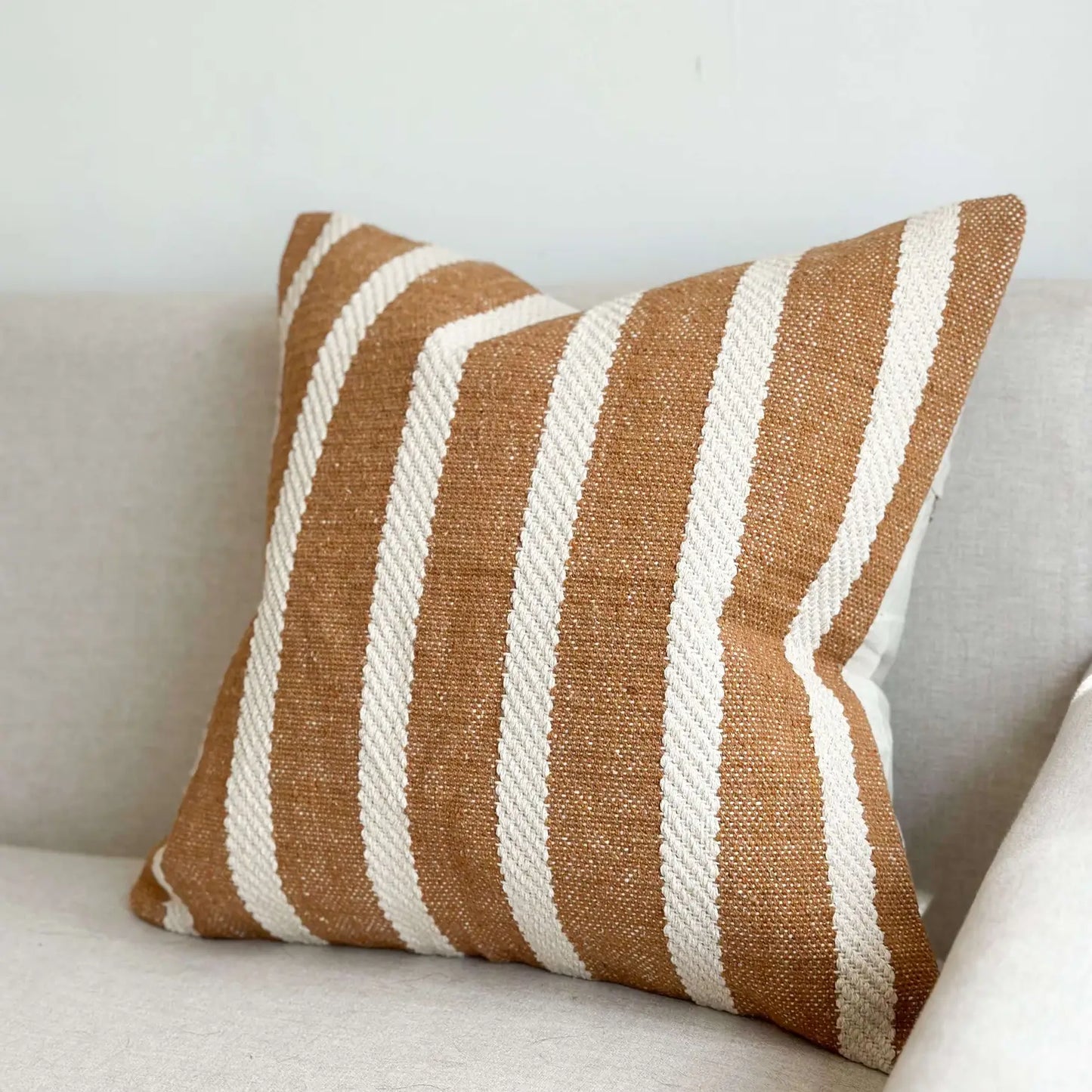 Striped brown and white pillow on a light-colored sofa