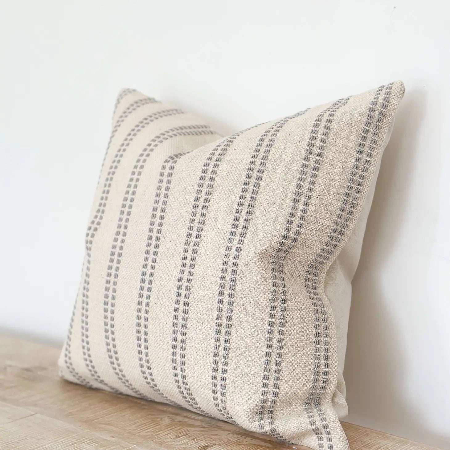 Beige pillow with gray stripes on a wooden surface