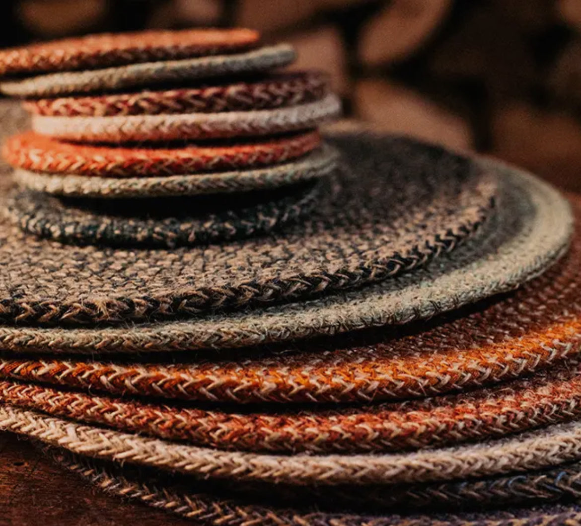 Stack of braided leather straps in various colors on a wooden surface.