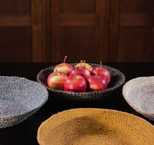 Bowl of apples on a dark surface with woven baskets around