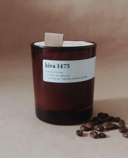 Candle labeled 'kiva 1475' with coffee beans on a beige background