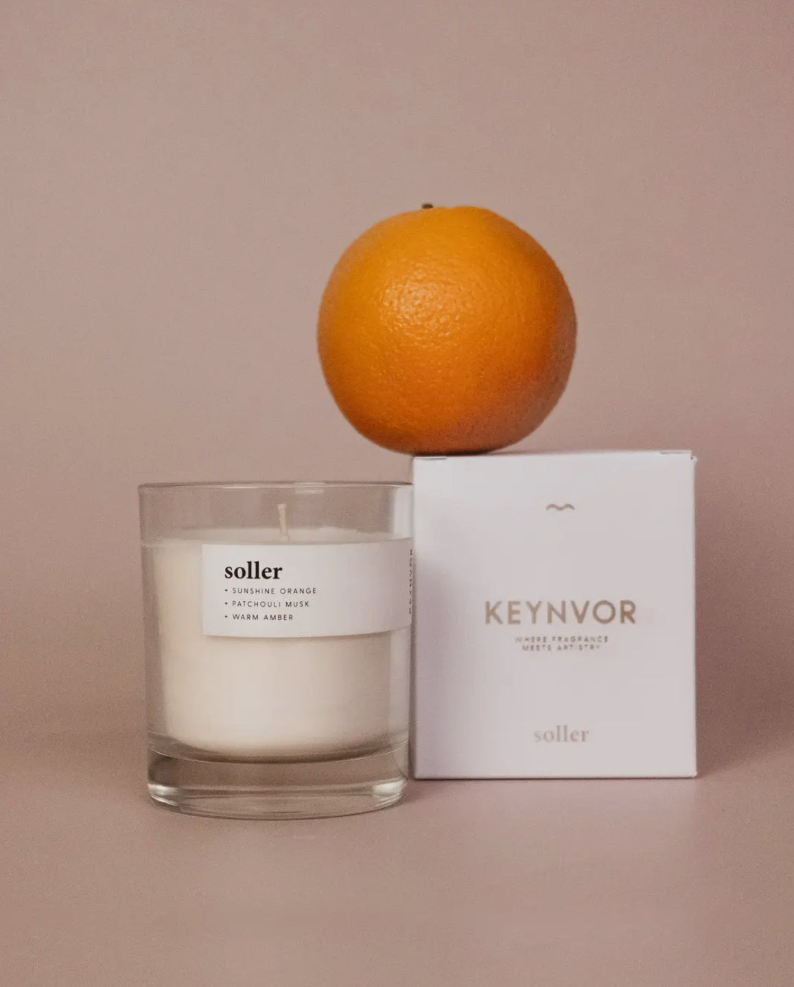 Candle with an orange on top and a 'Keynvor' box on a beige background