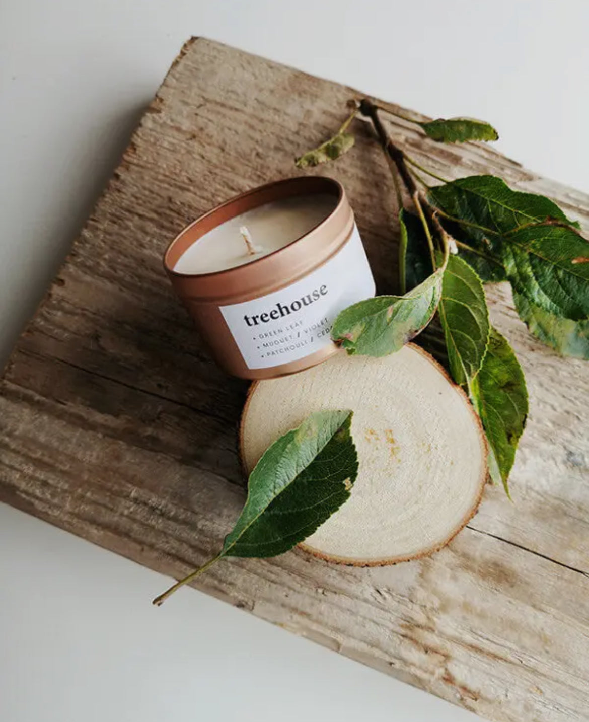 Keynvor Travel Tin Candle labeled 'treehouse' on a wooden surface with leaves