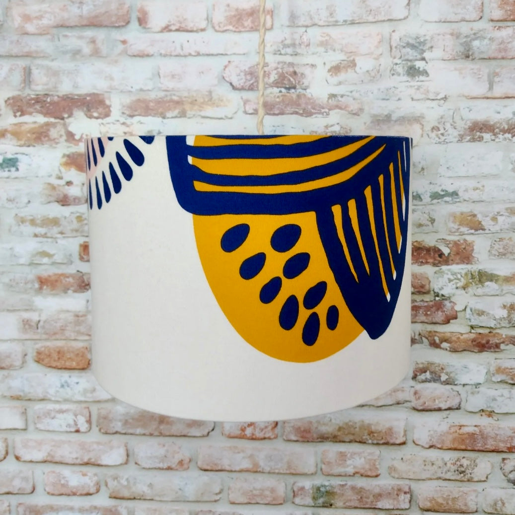 Decorative lampshade with blue and yellow abstract design on a brick wall background