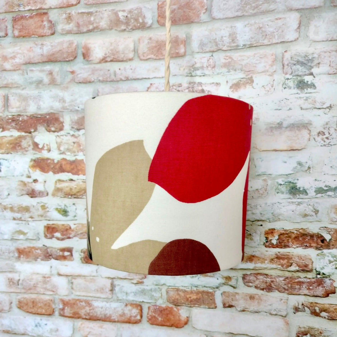 Decorative lampshade with abstract shapes against a brick wall