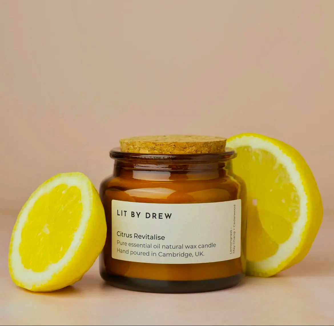 Candle jar labeled 'Lit by Drew' with lemon slices on a beige background