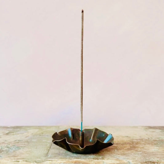 Incense stick in a decorative Lotus Incense Holder on a wooden surface with a light background