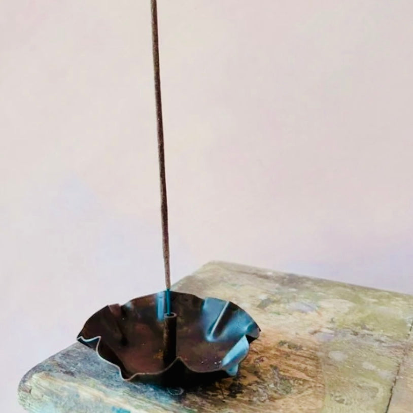 Incense stick in a Lotus Incense Holder on a textured surface with a plain background