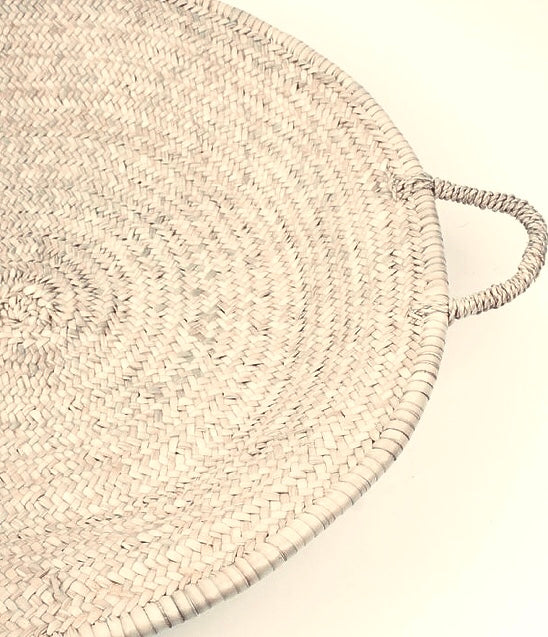 Round woven mat with handles on a light background
