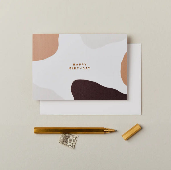 Greeting card with 'Happy Birthday' text, pen, and stamp on a beige background