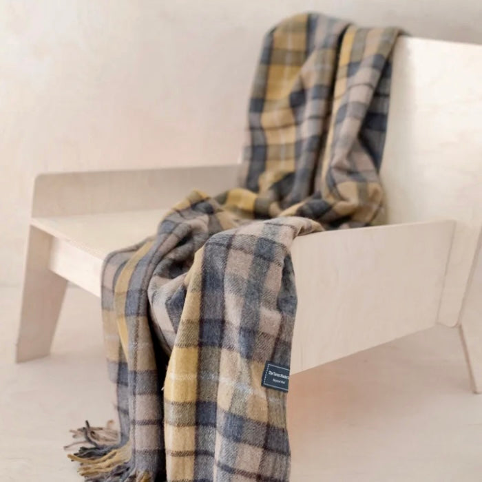 Plaid blanket draped over a white chair with a visible brand label.