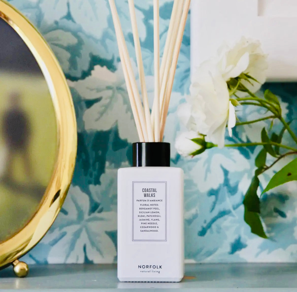 Reed Diffuser Set - Coastal Walks with 'Coastal Walks' and 'Norfolk' branding on a decorative surface with flowers and a mirror.