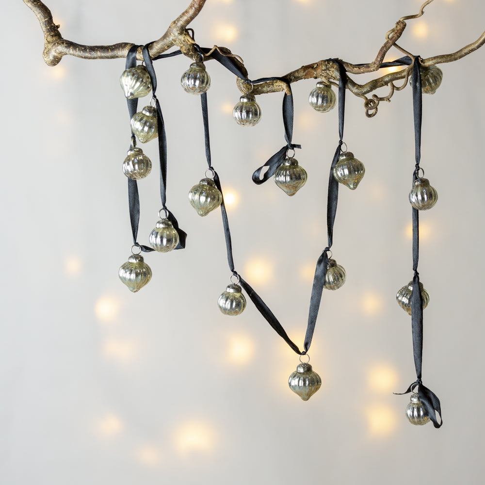 Decorative branch with silver ornaments and black ribbons against a soft light background