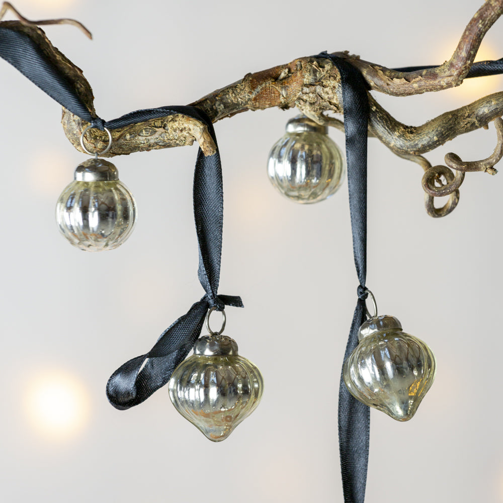 Decorative branch with glass ornaments and black ribbons on a light background