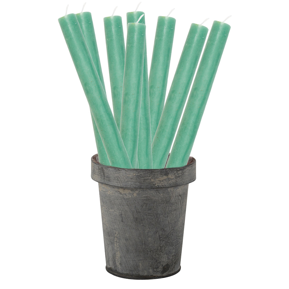 Green candles in a rustic metal container on a white background